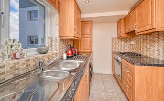 Modern kitchen with wooden cabinets, granite countertops, stainless steel appliances, and a window overlooking the street