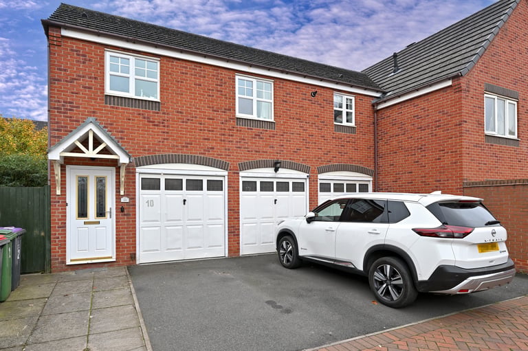 Modern red brick house with white garage doors and a white SUV parked on the driveway